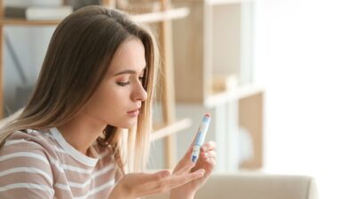 Das Bild zeigt eine junge Frau beim Blutzuckerselbsttest als Symbolbild für die Diabetesbehandlung in Deutschland.