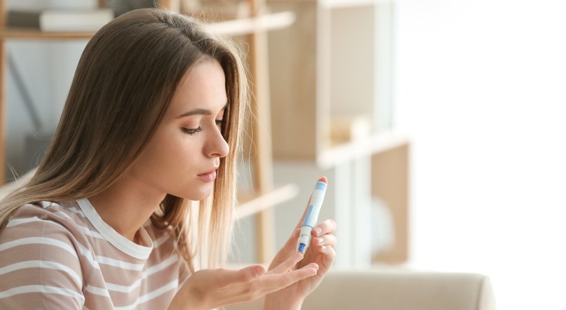 Das Bild zeigt eine junge Frau beim Blutzuckerselbsttest als Symbolbild für die Diabetesbehandlung in Deutschland.
